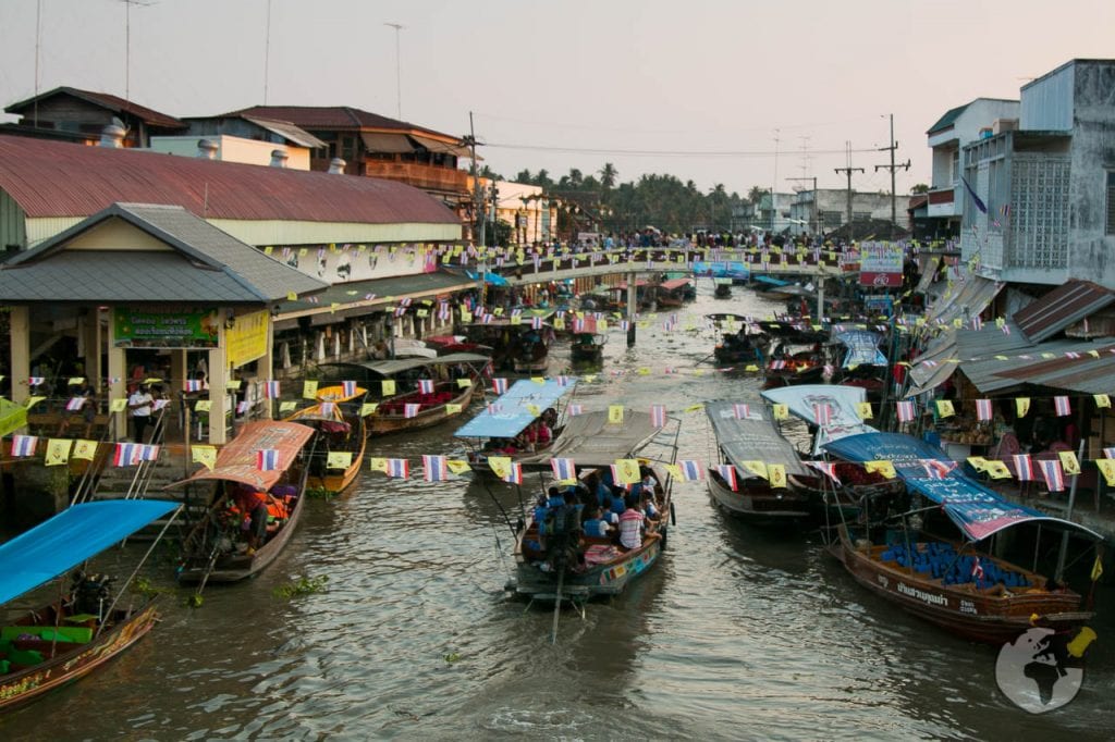Barcos com tendas coloridas navegando em um canal estreito repleto de comerciantes no mercado flutuante de Bangkok.