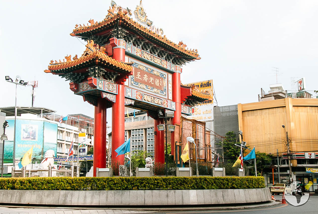 Portal tradicional chinês com pilares vermelhos em meio a prédios de Bangkok, marcando a entrada de Chinatown.