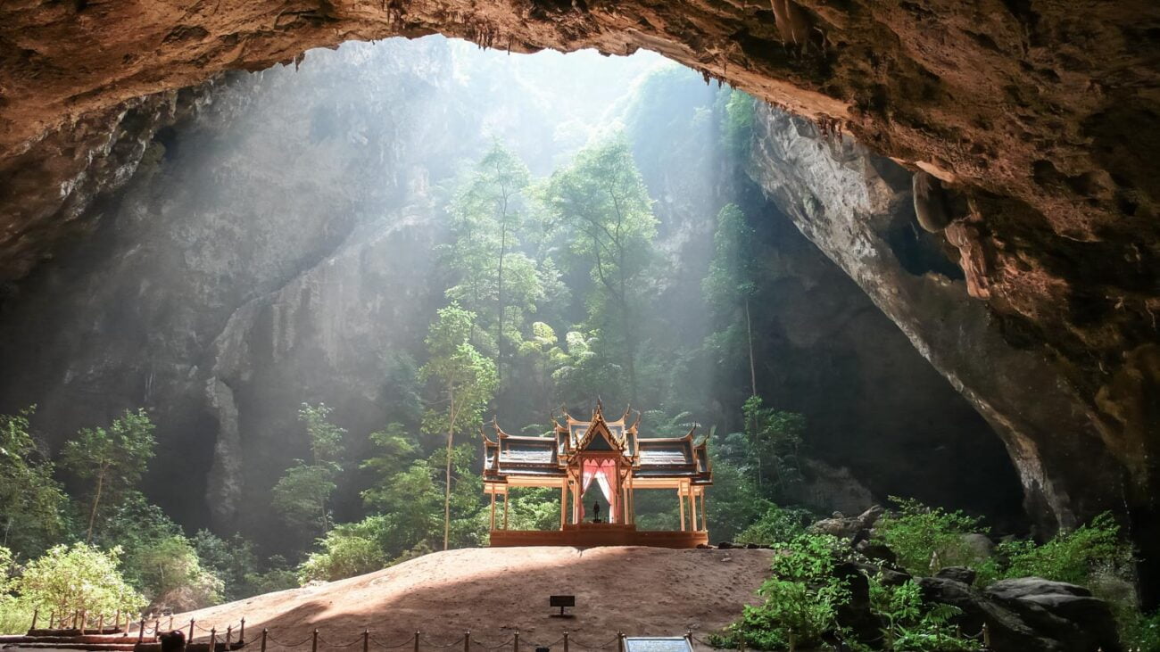 Templo real construído dentro da caverna Phraya Nakhon, iluminado por feixes de luz natural que entram por uma abertura no teto.