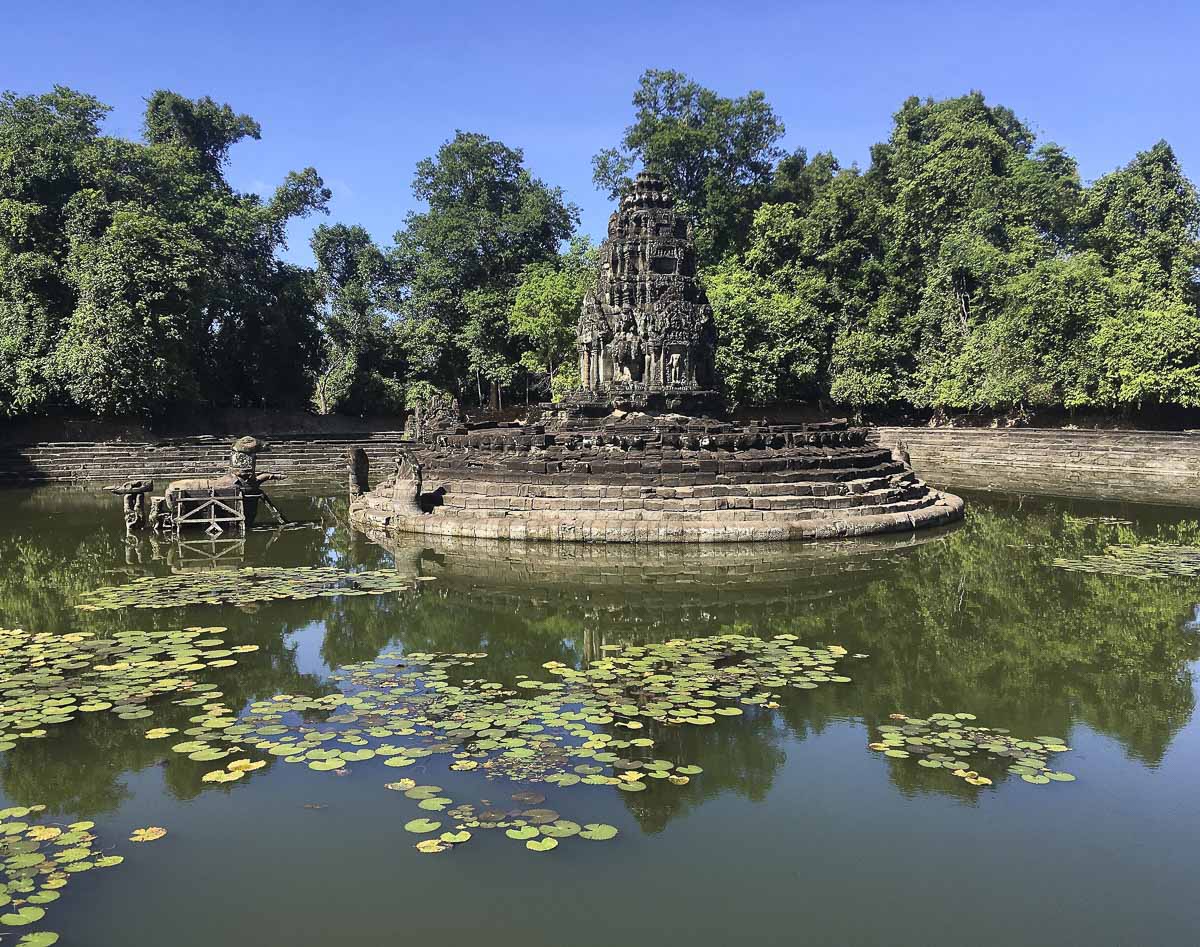 Pequeno templo circular de Neak Pean cercado por um lago coberto de vitórias-régias.