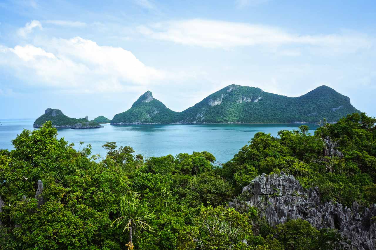  Ilhas cobertas por floresta vistas do alto, cercadas por mar calmo em tons azul-esverdeados no Ang Thong Marine Park, próximo a Koh Phangan.