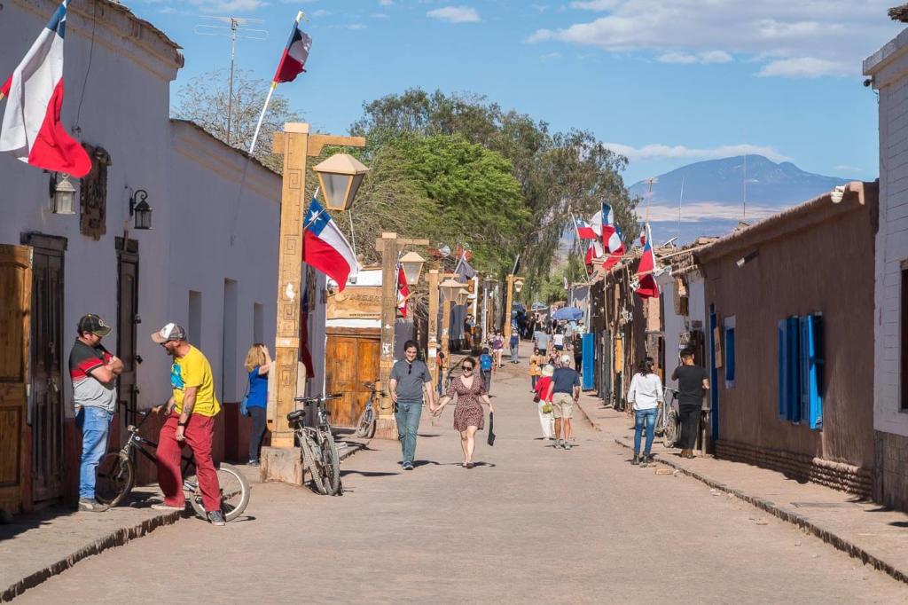 Deserto do Atacama Chile - Calle Caracoles é a rua mais movimentada de San Pedro de Atacama, com construções baixa, chão de terra pessoas circulam buscando restaurante, agências de passeios e hotéis