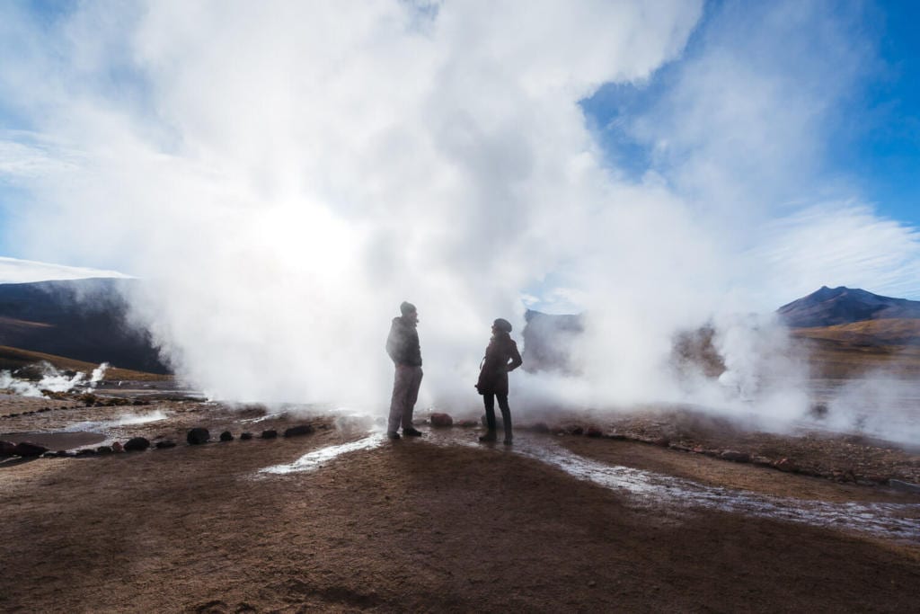 Deserto do Atacama Chile - Foto Caio e Adriana em meio a fumaça liberada pelo vapor dágua no clima frio da manhã no Geyser Del Tatio
