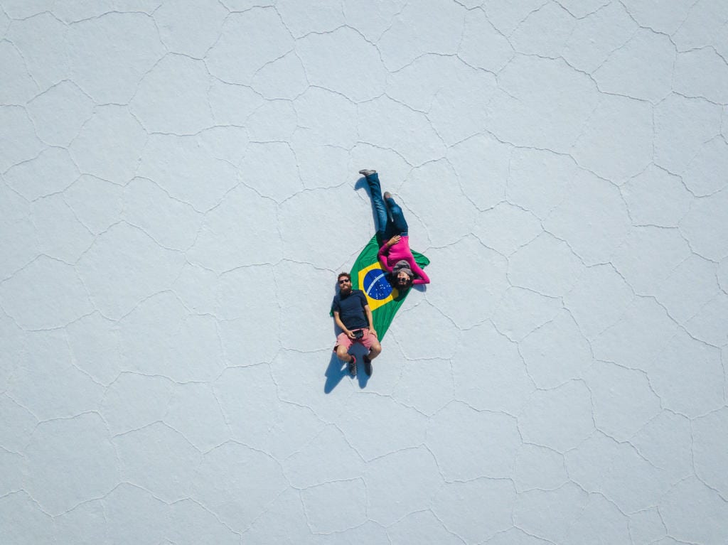 Salar de Uyuni - Foto do Caio e da Adriana deitados sobre uma bandeira do Brasil no meio do deserto de Sal