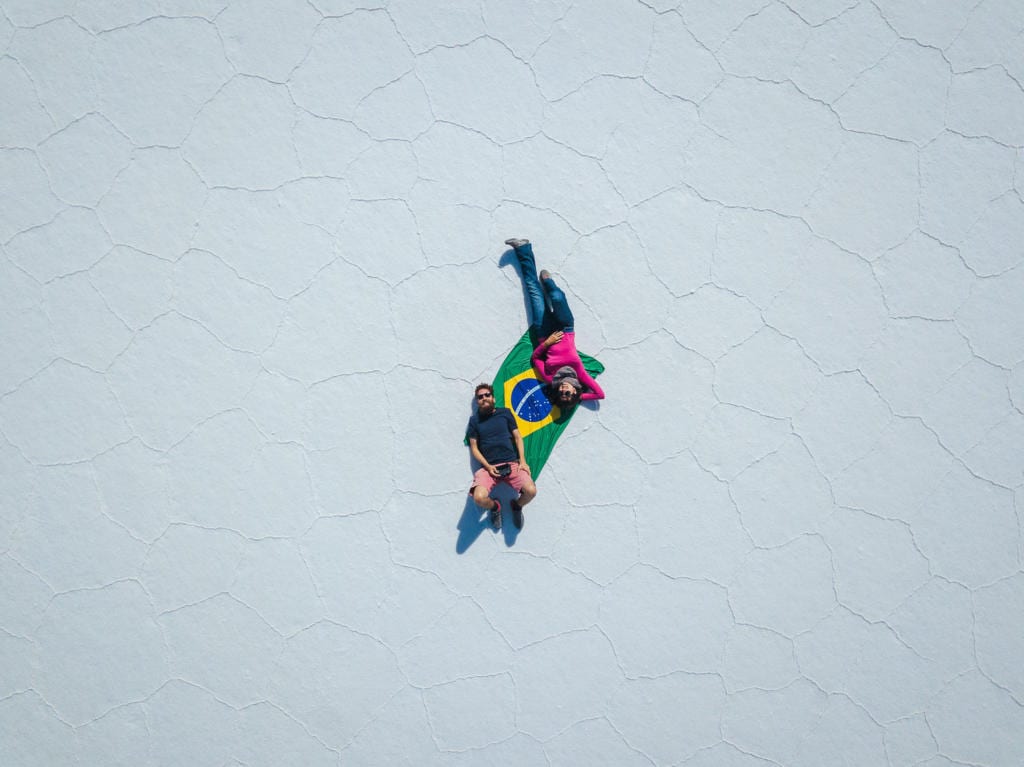 Salar de Uyuni - Foto do Caio e da Adriana deitados sobre uma bandeira do Brasil no meio do deserto de Sal