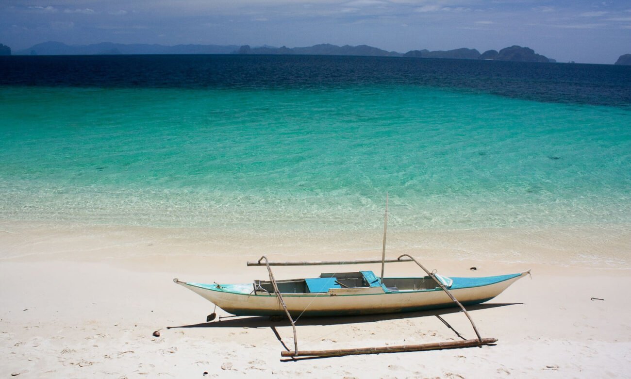 Foto de um barco filipino na água cristalina - Coron Filipinas