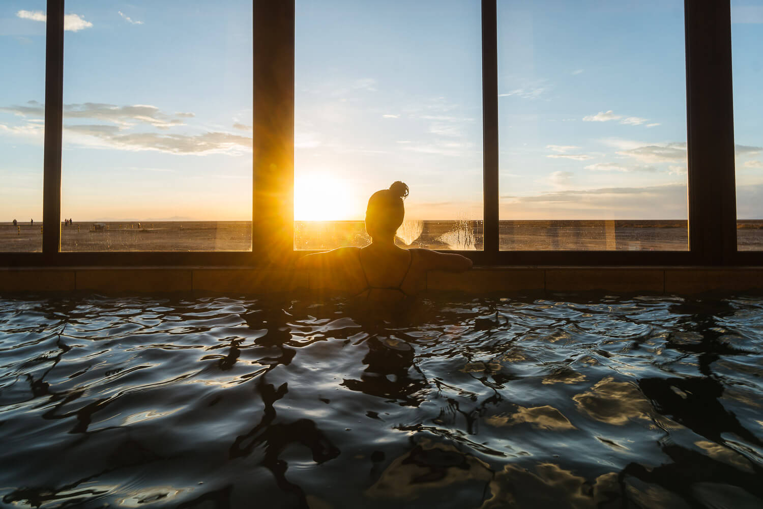 Foto da Dro observando o pôr do sol de dentro da piscina - hotel de sal no Uyuni