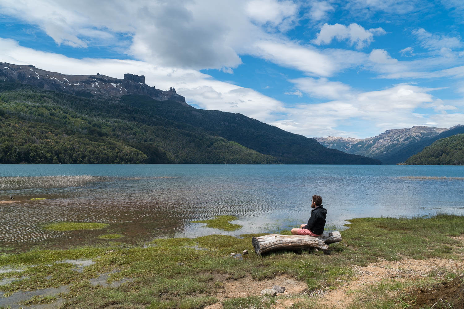 Foto Caio sentado em um tronco a margem do Lago - Rota dos Sete Lagos