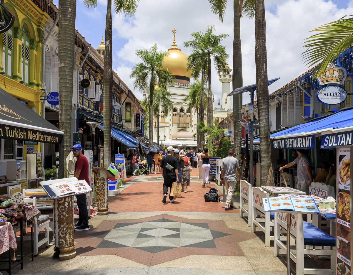 Rua colorida com restaurantes e vista da Mesquita do Sultão em Singapura.