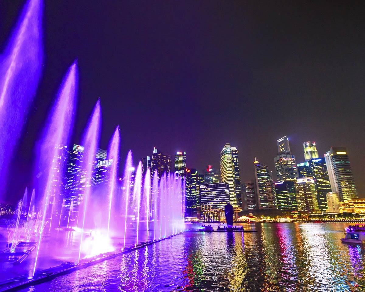 Show de luzes coloridas refletidas na água da Marina Bay à noite em Singapura.