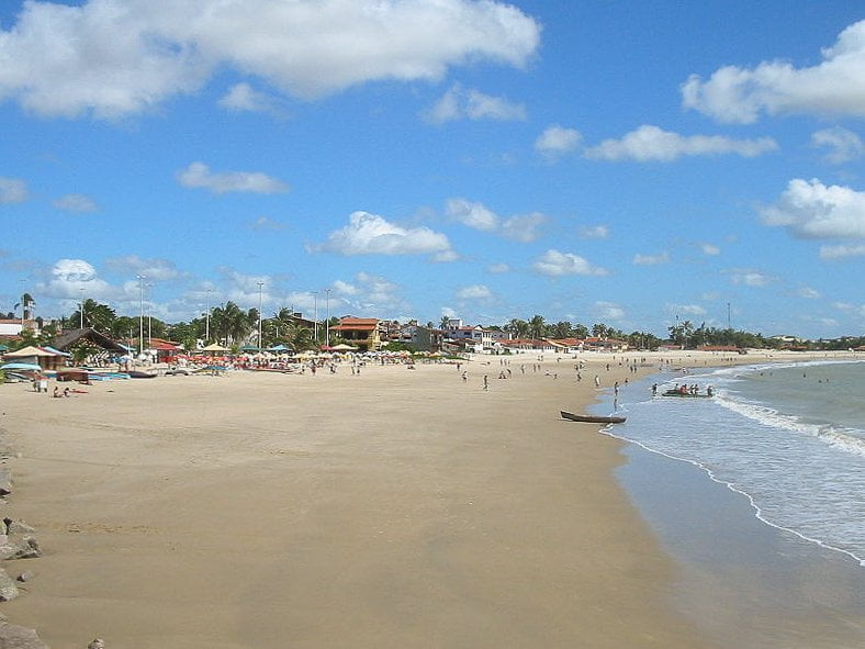 Praia rodeada por casas e mar calmo