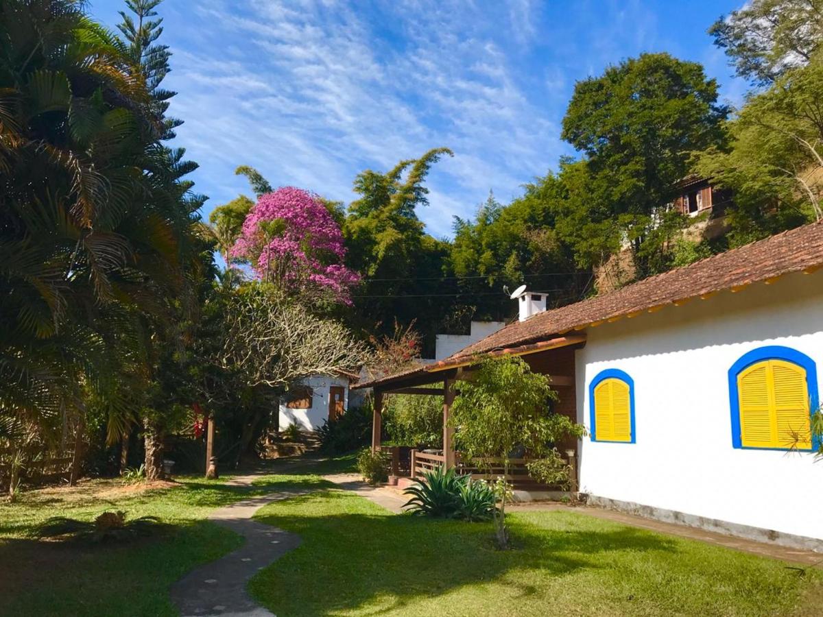 Área externa gramada cercada por jardins em hostel em Itaipava