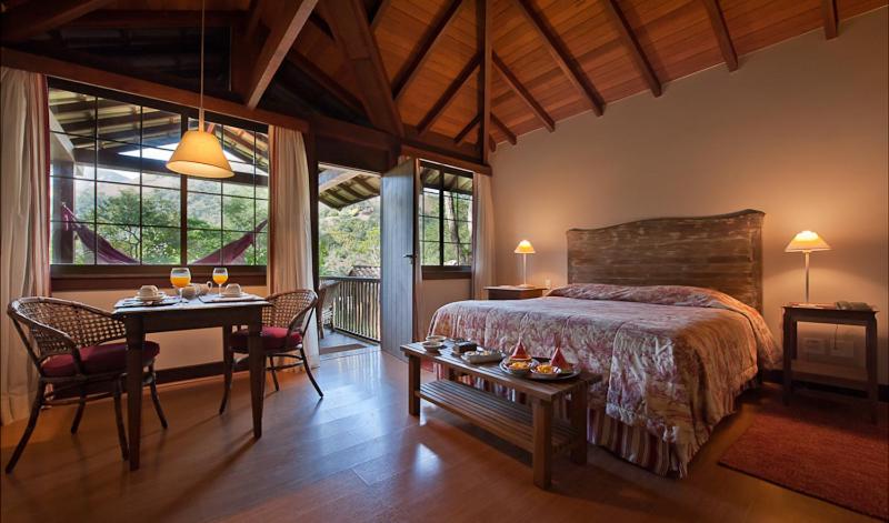 Quarto amplo com decoração rústica e vista da natureza em pousada em Itaipava