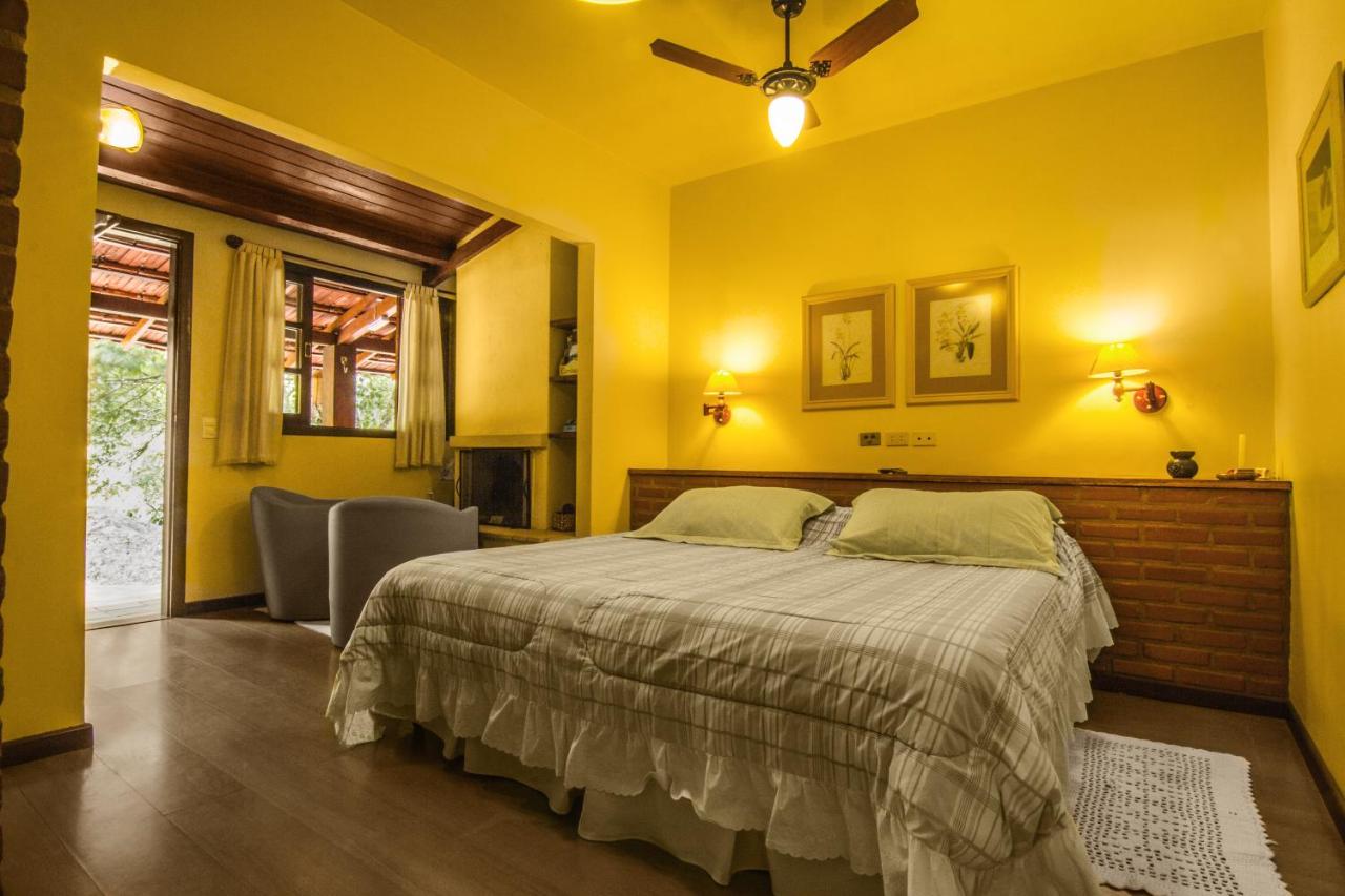 Quarto com paredes amarelas e cama de casal grande em pousada em itaipava
