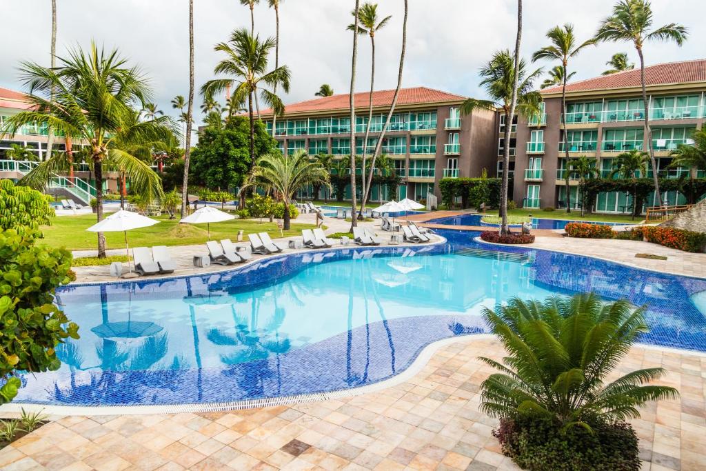 Piscina ao ar livre cercada por jardins em resort em Porto de Galinhas 