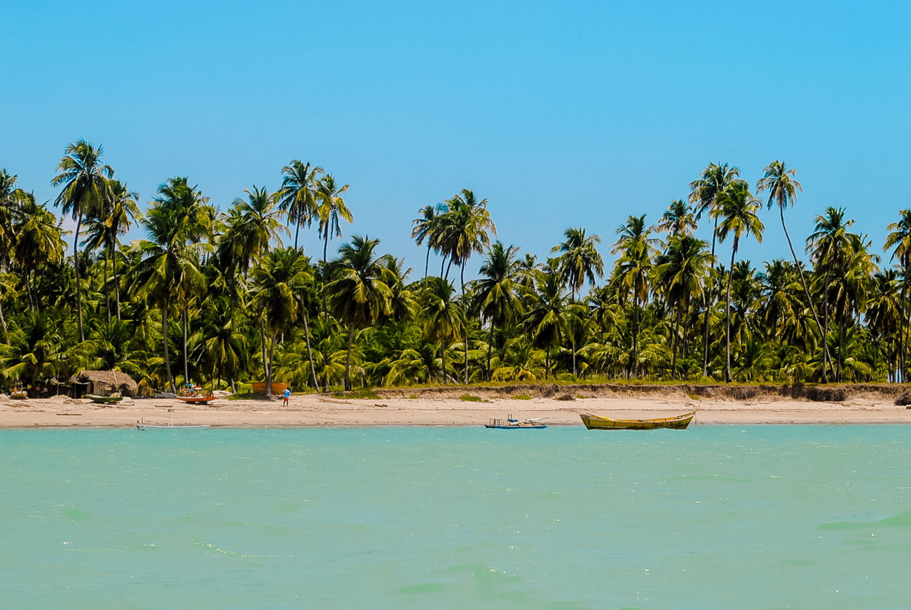 Praia de Ipioca em Maceió cercada por vegetação e águas cristalinas