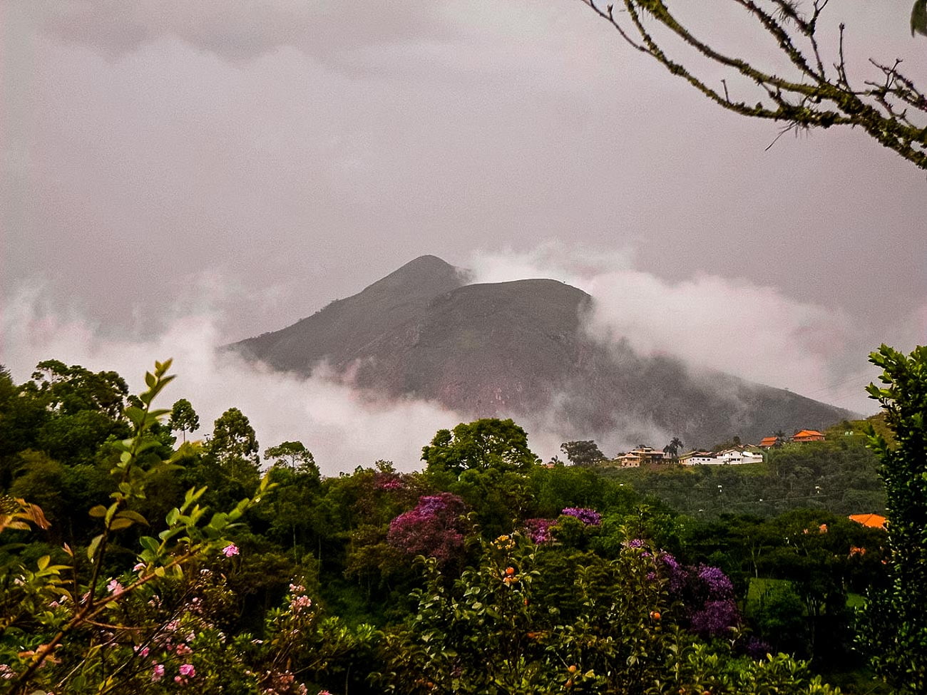 Formação rochosa da Pedra de Itaipava entre nuvens e floresta
