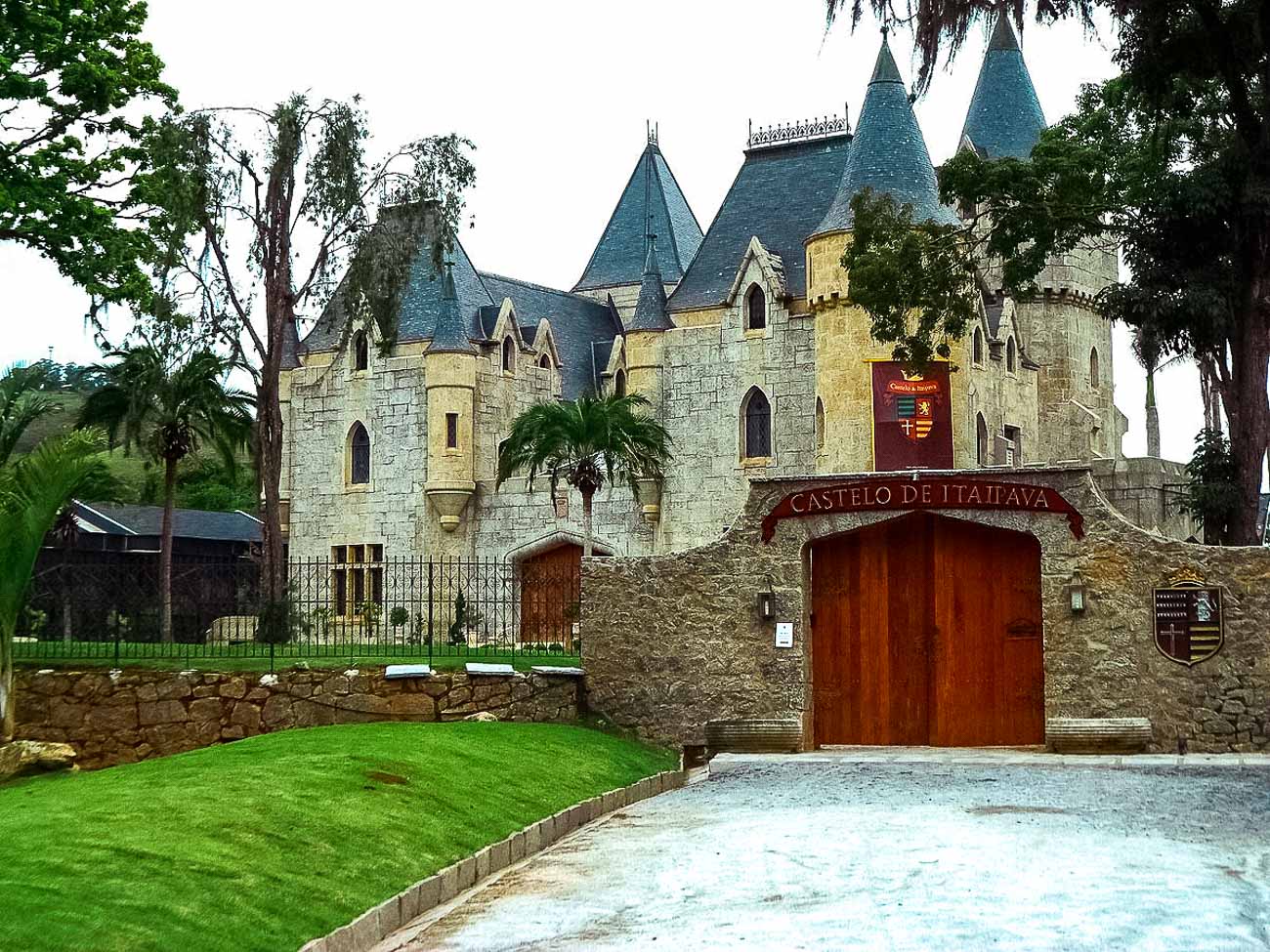Castelo de Itaipava com torres e portão de madeira com pedra