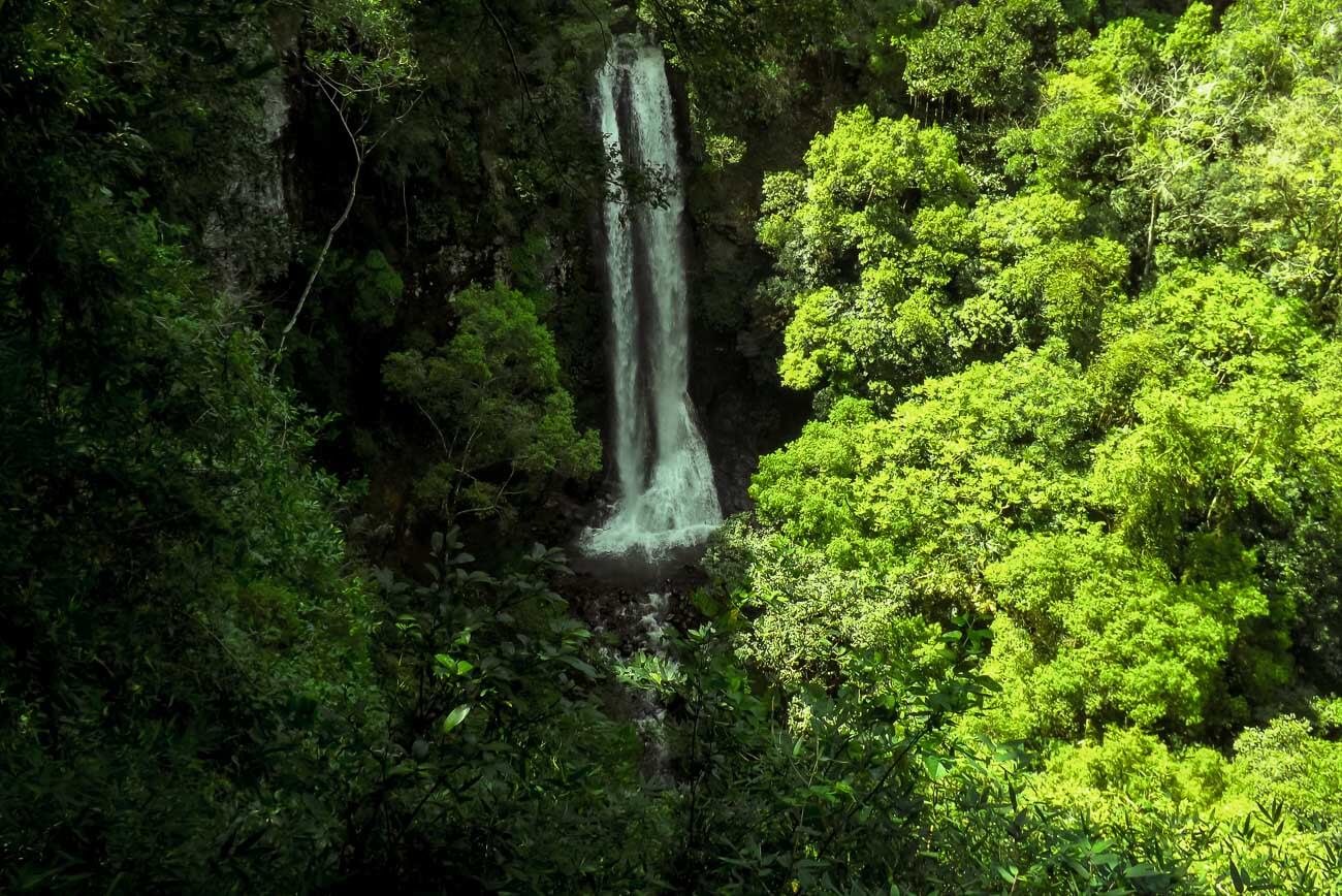 Queda d'água da Cachoeira do Trombão entre montanhas cercadas por vegetação 