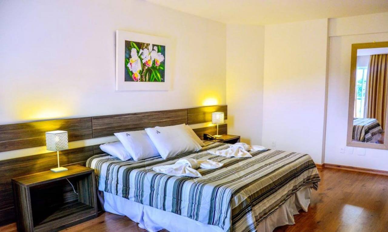 Quarto com cama de casal e decoração simples em hotel em Teresópolis