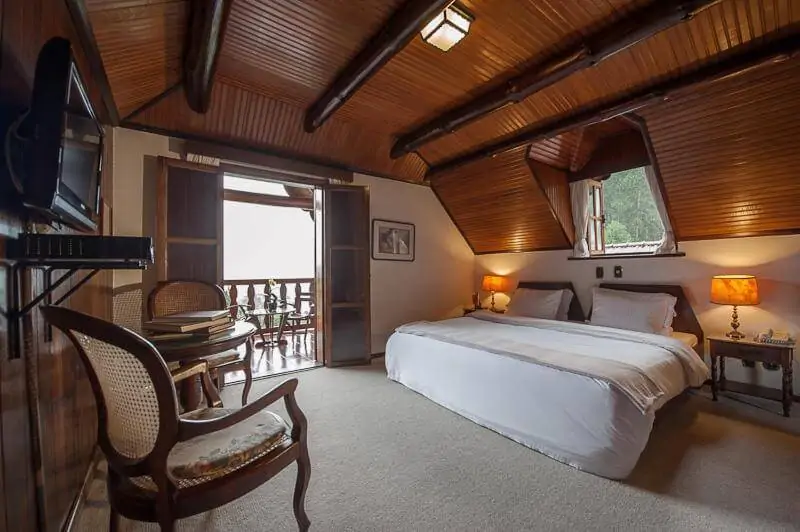 Quarto grande de casal com decoração rústica e elegante com sacada com vista em hotel em Teresópolis