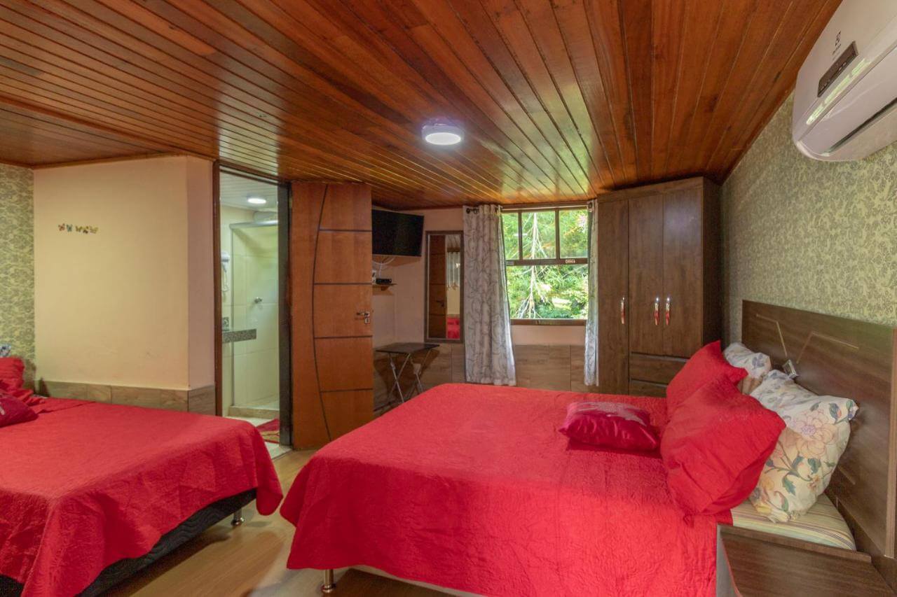 Quarto com duas camas de casal e piso e tetos de madeira