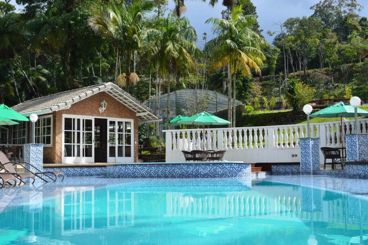 Piscina ao ar livre em pousada em teresópolis cercada por árvores