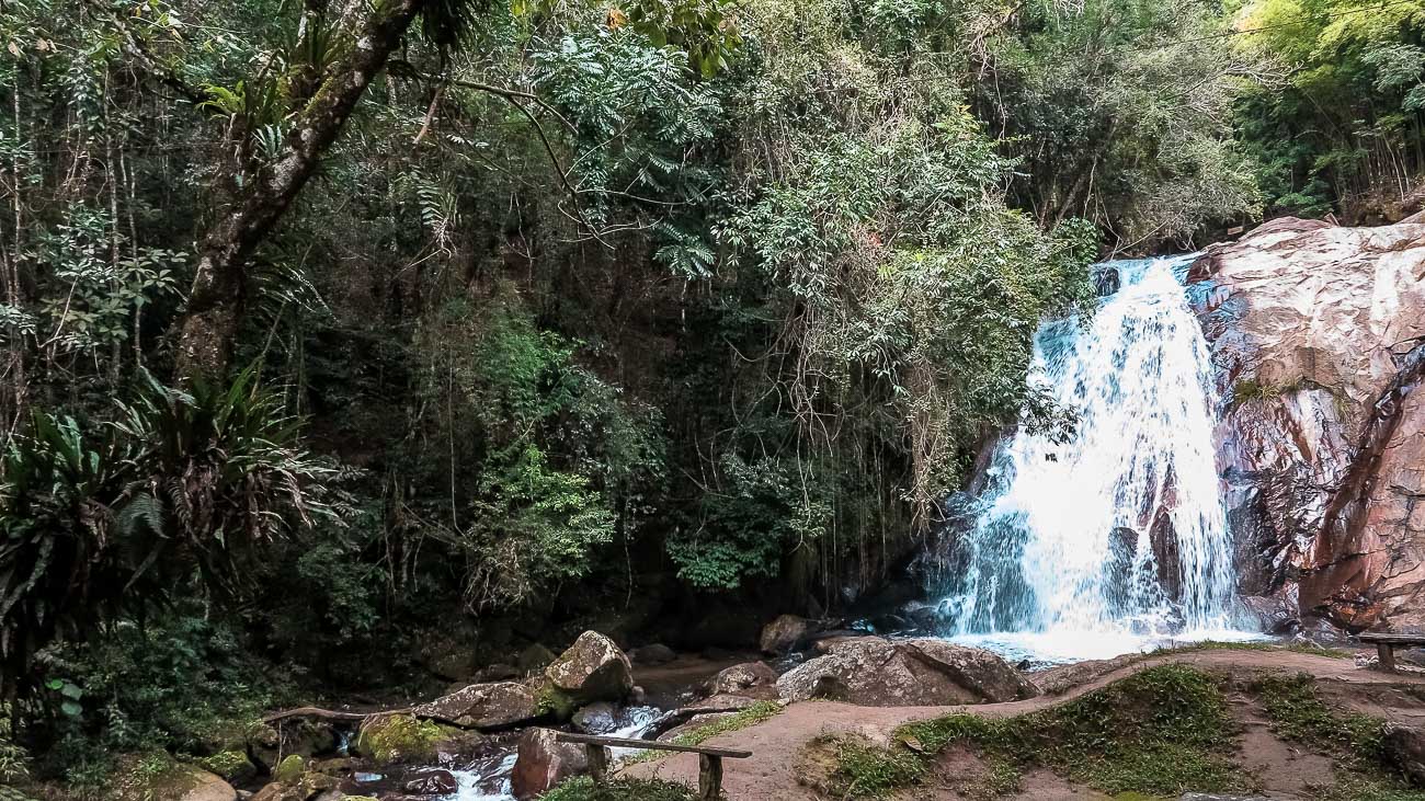 Pequena queda de cachoeiras, cercada por vegetação.