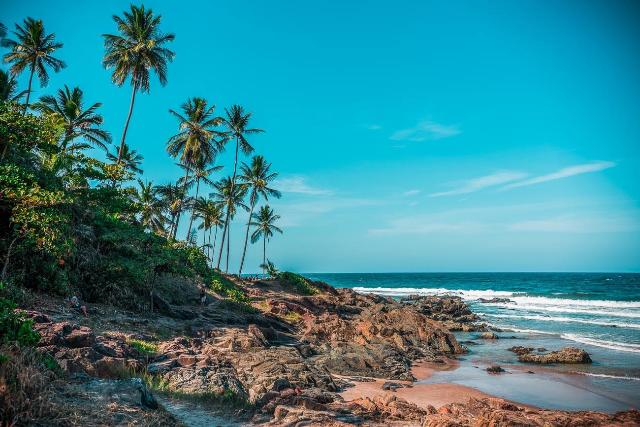 Praia do Tiririca com pedras no mar e coqueiros na orla