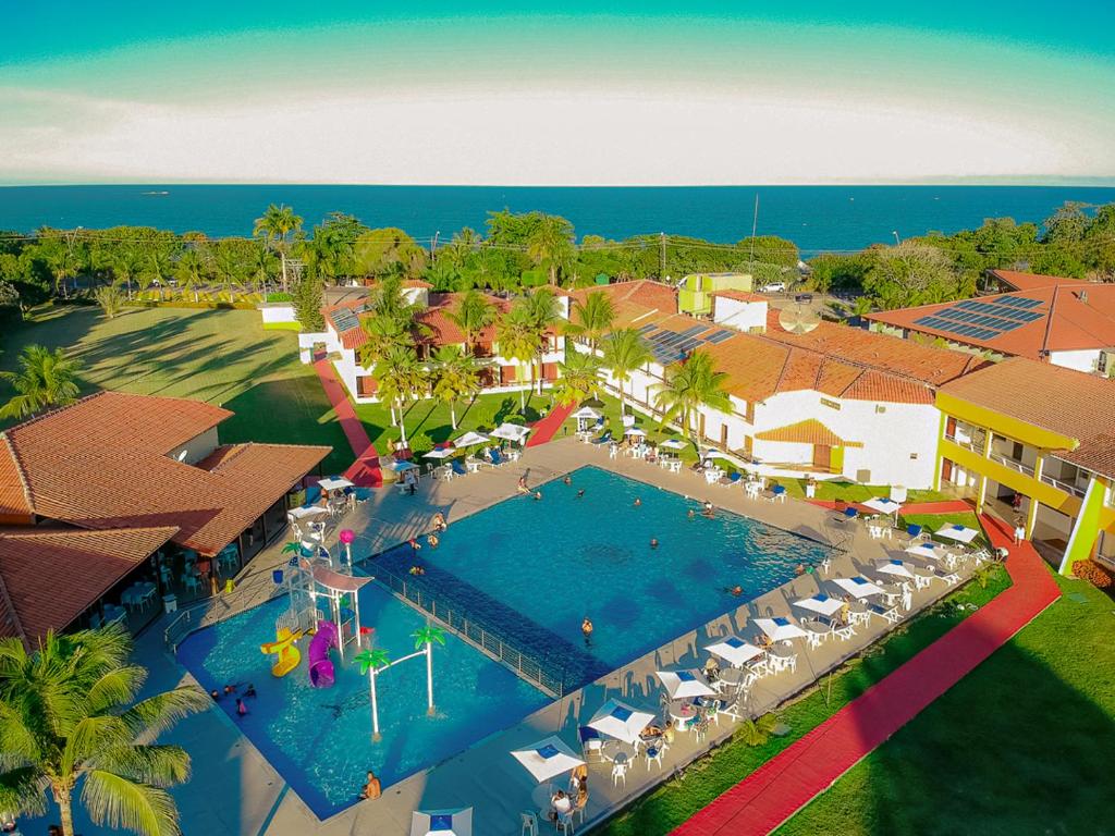 Vista de cima de piscina e praia ao fundo em resort em Porto Seguro