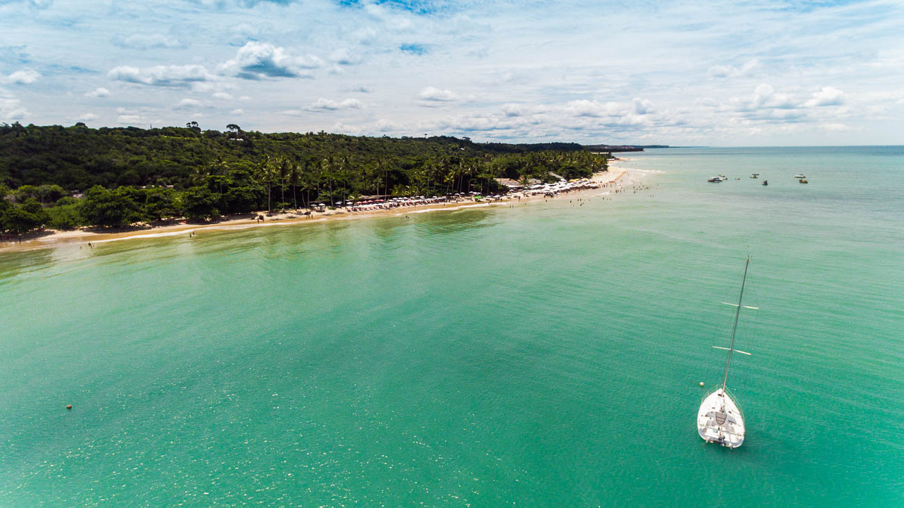 Vista de cima da Praia dos Coqueiros, em Trancoso, com mar de águas azuis esverdeadas