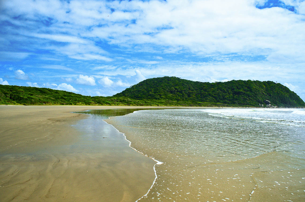 Faixa de areia com mar tranquilo na Praia do Miguel na Ilha do Mel