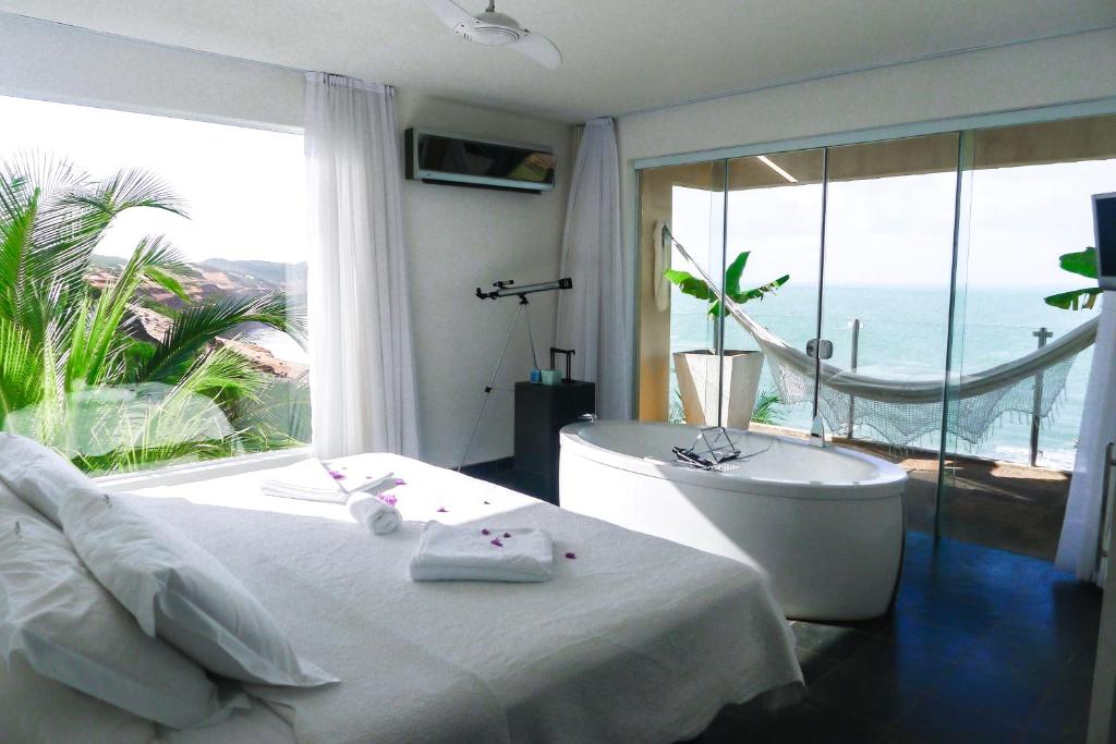 Quarto com decoração clean e banheira de hidromassagem com vista para o mar