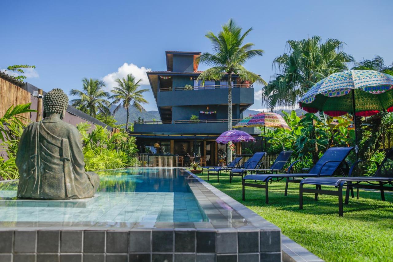 Piscina ao ar livre em área gramada e ao fundo pousada