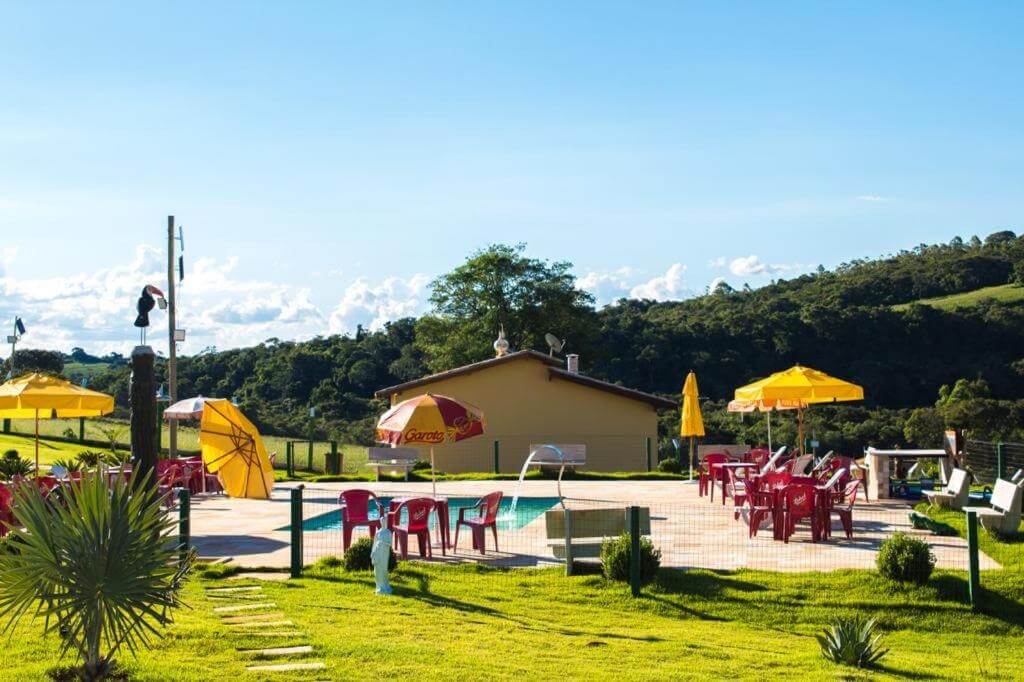 Piscina ao ar livre com mesas e cadeiras em sua volta 