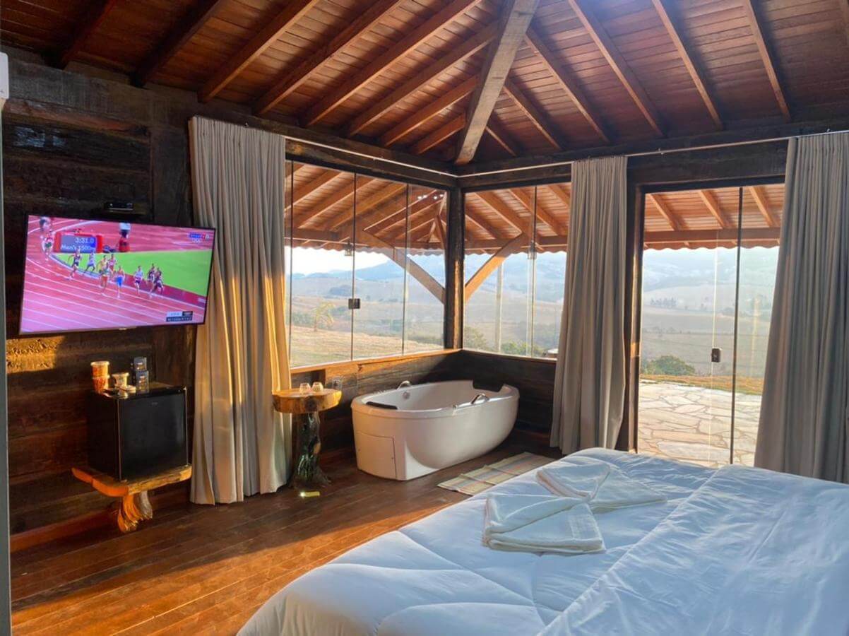 Quarto de casal com vista para a natureza e banheira em pousada em São Thomé das Letras