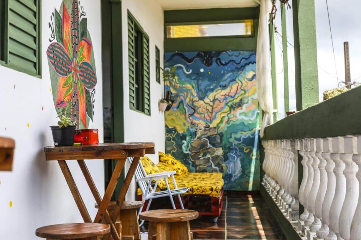 Varanda com mesas e cadeiras de madeira em hostel em São Thomé das Letras