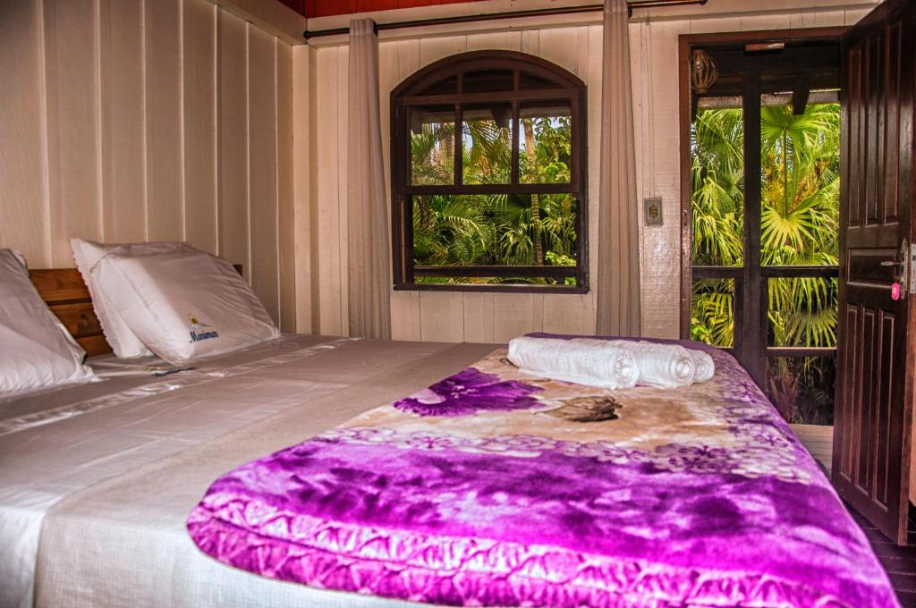Cama de casal em quarto com sacada com vista para a natureza na Ilha do Mel