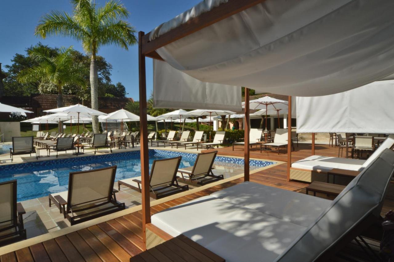 Piscina ao ar livre em deck de madeira com cabanas e espreguiçadeiras