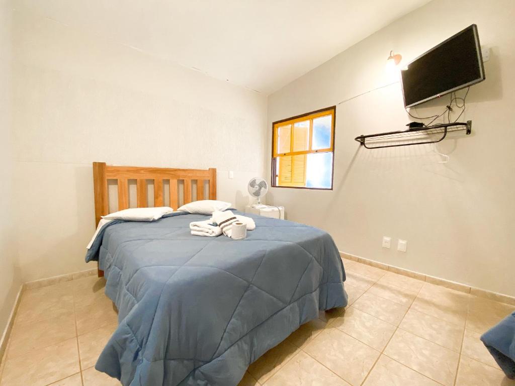 Cama de casal com edredom azul e toalhas na cama em quarto bem iluminado em hotel em São Thomé das Letras