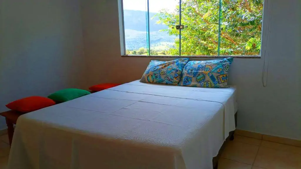 Quarto com cama de casal e janela com vista para a natureza