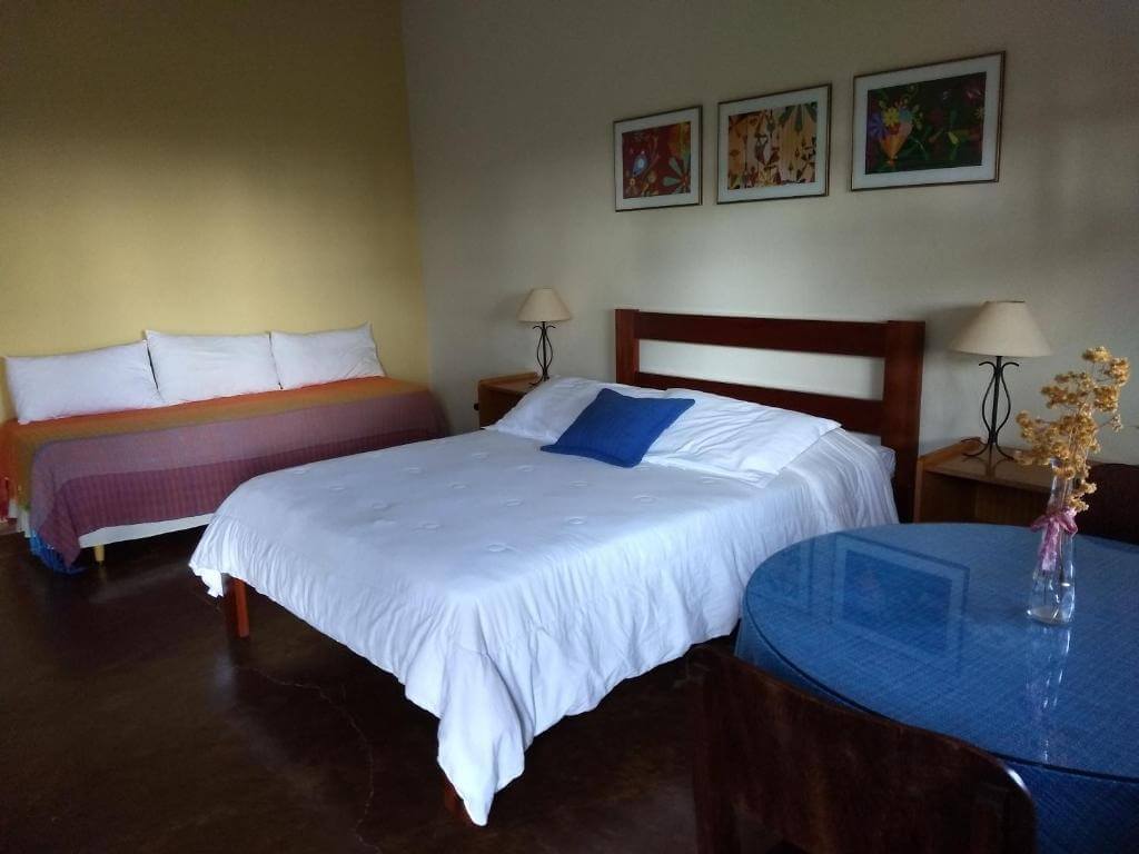 Quarto com cama de casal e solteiro, e mesa em pousada na Serra da Canastra