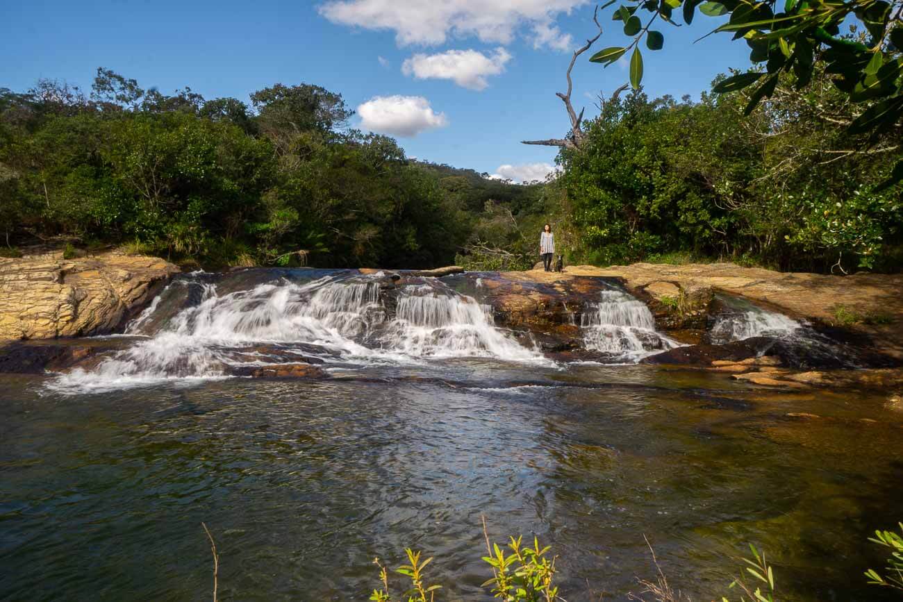 Quedas d´águas da Cachoeira dos Índios em Carrancas com uma mulher e um cachorro em sua base