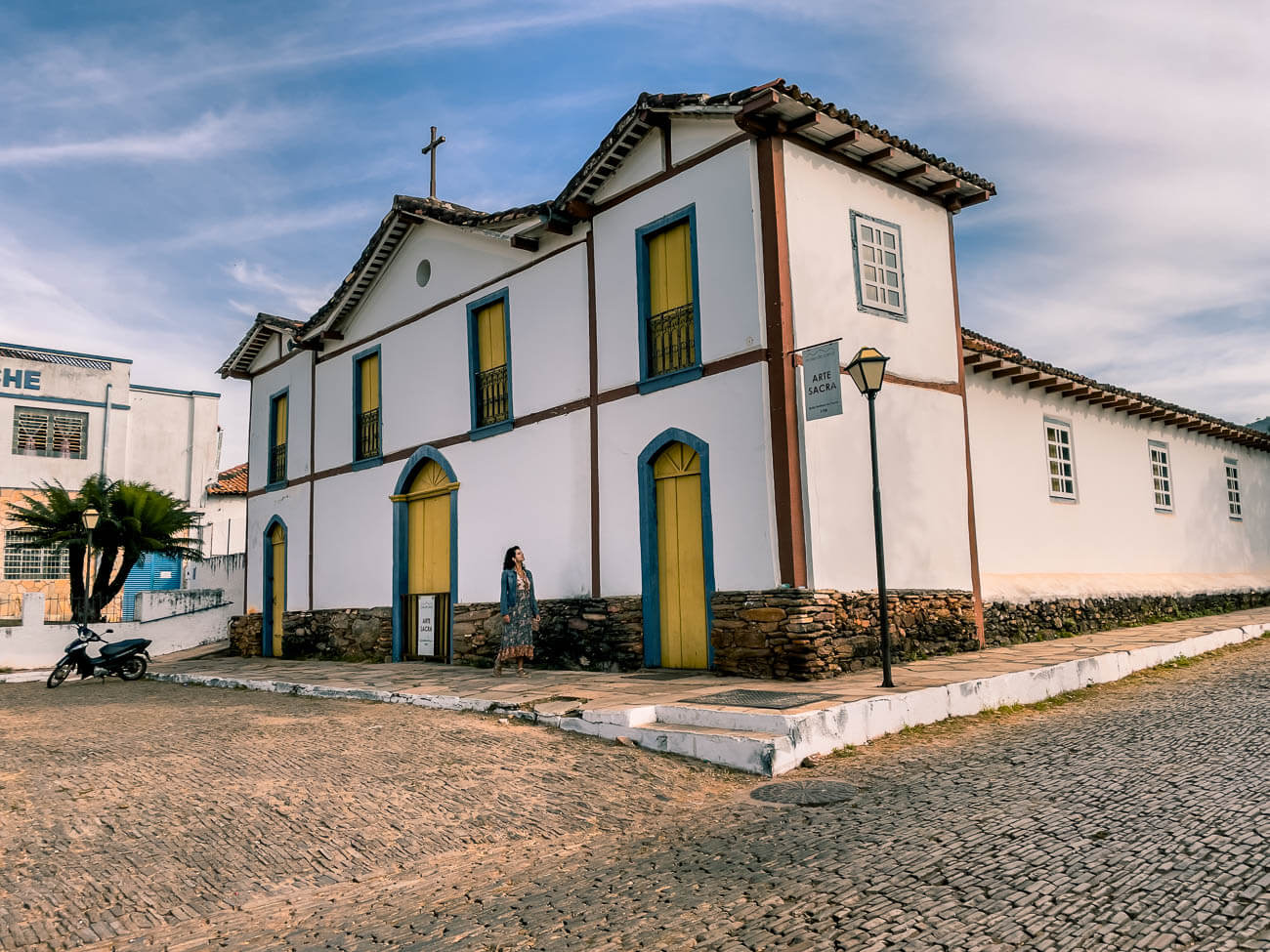 Fachada de arquitetura colonial da Igreja e Museu Arte Sacra em Pirenópolis com uma mulher caminhando na frente