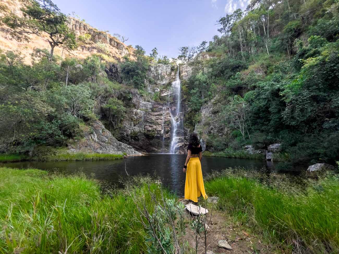 Mulher em pé de frente para o poço e queda d´água da Cachoeira do Nego