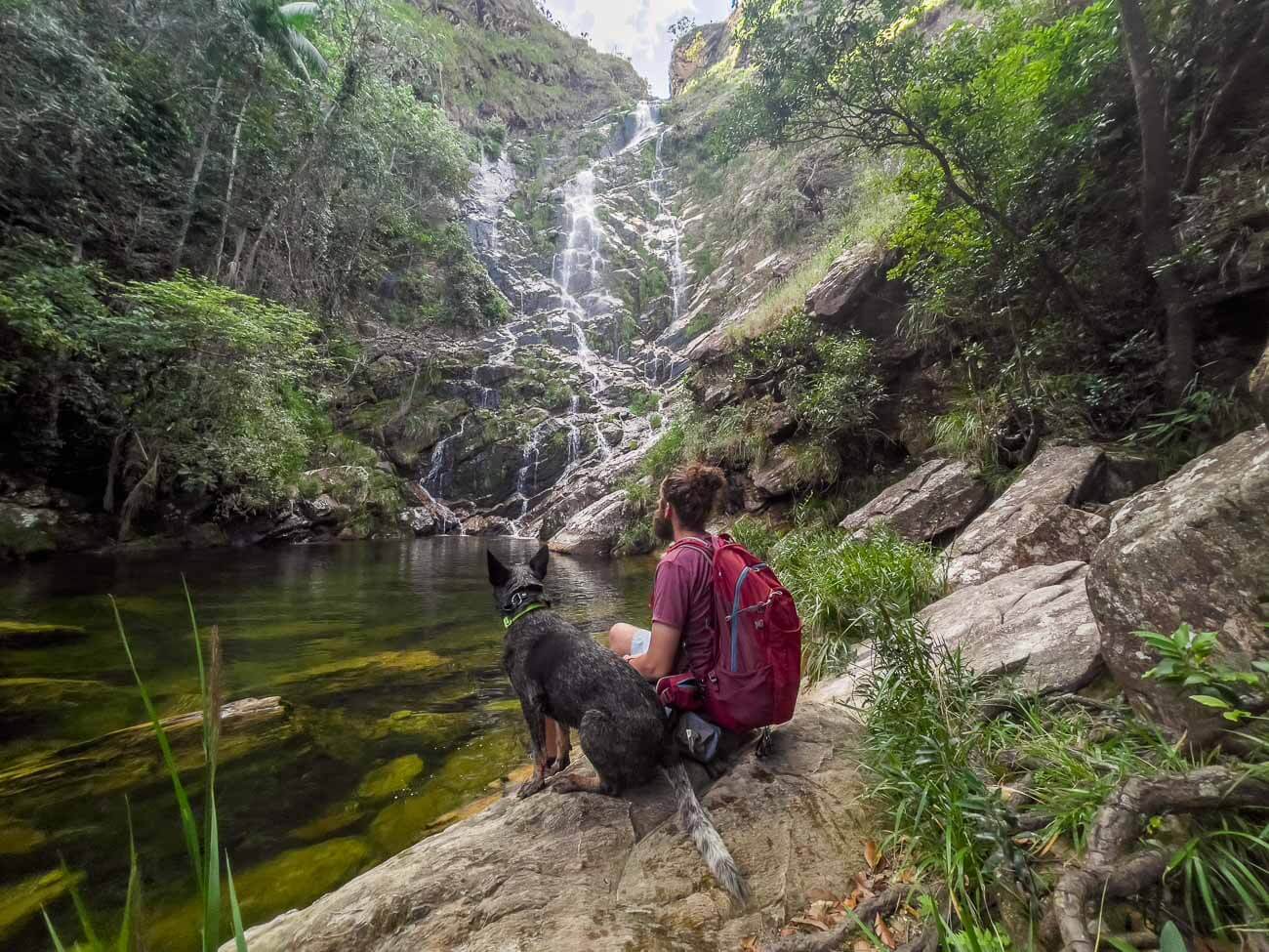 Homem e cachorro sentados em uma das pedras da Cachoeira da Lavrinha