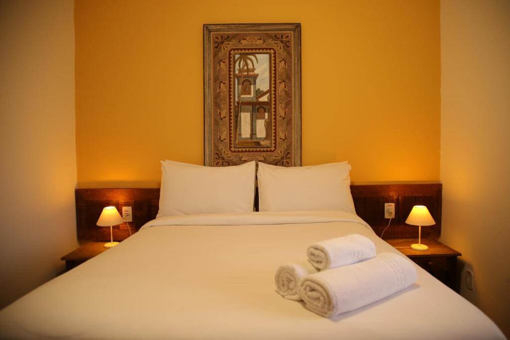 Cama de casal com mesas de cantos e quadro decorativo