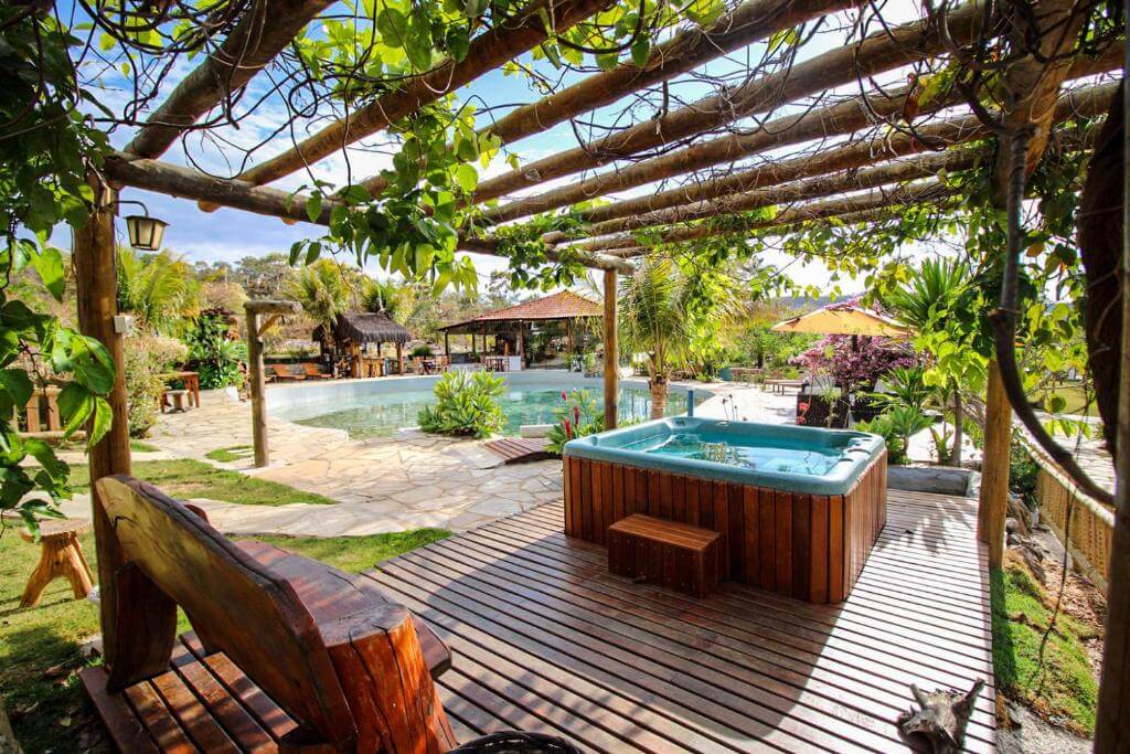 Área externa com deck de madeira, jacuzzi e piscina em pousada em Pirenópolis