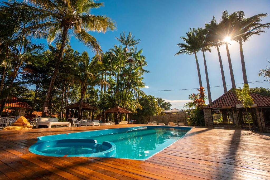 Piscina ao ar livre em deck de madeira, cercada por coqueiros