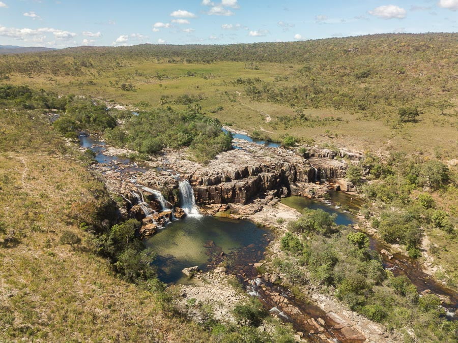 Vista área do poço e queda d'água da Cachoeira da Muralha cercada pela natureza